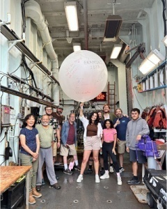 A group of people standing in a room with a large white balloon